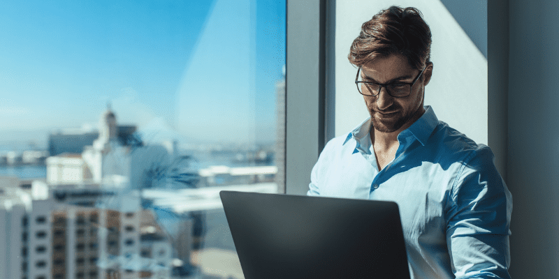 man with computer overlooks city skyline